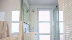 A modern bathroom with a glass shower enclosure, a white sink, and a large window. - Holiday Home in Nijkerk With Terrace (Nijkerk)