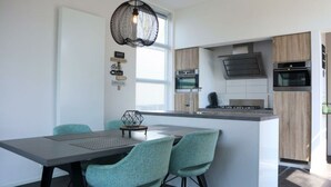 A modern kitchen with a central island, two ovens, and a hanging light fixture. - Holiday Home in Nijkerk With Terrace (Nijkerk)