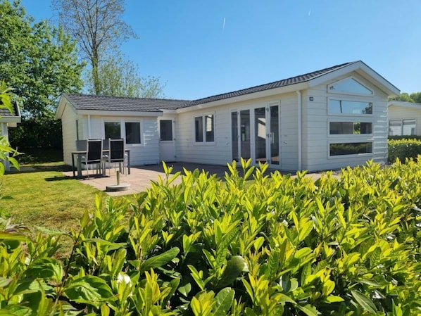 A modern single-story mobile home with a patio, a dining area, and a well-maintained garden. - Holiday Home in Halfweg With Terrace (Halfweg)