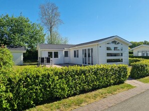 A single-story mobile home with a flat roof, large windows, and a small porch area. - Holiday Home in Halfweg With Terrace (Halfweg)