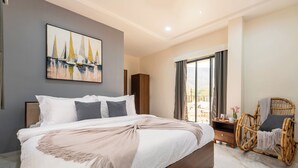 Un dormitorio con una cama grande, un armario de madera, una silla de mimbre y un cuadro de un paisaje urbano en la pared.