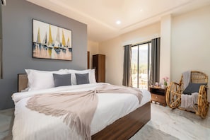 Un dormitorio con una cama grande, un armario de madera, una silla de mimbre y un cuadro de un paisaje urbano en la pared.