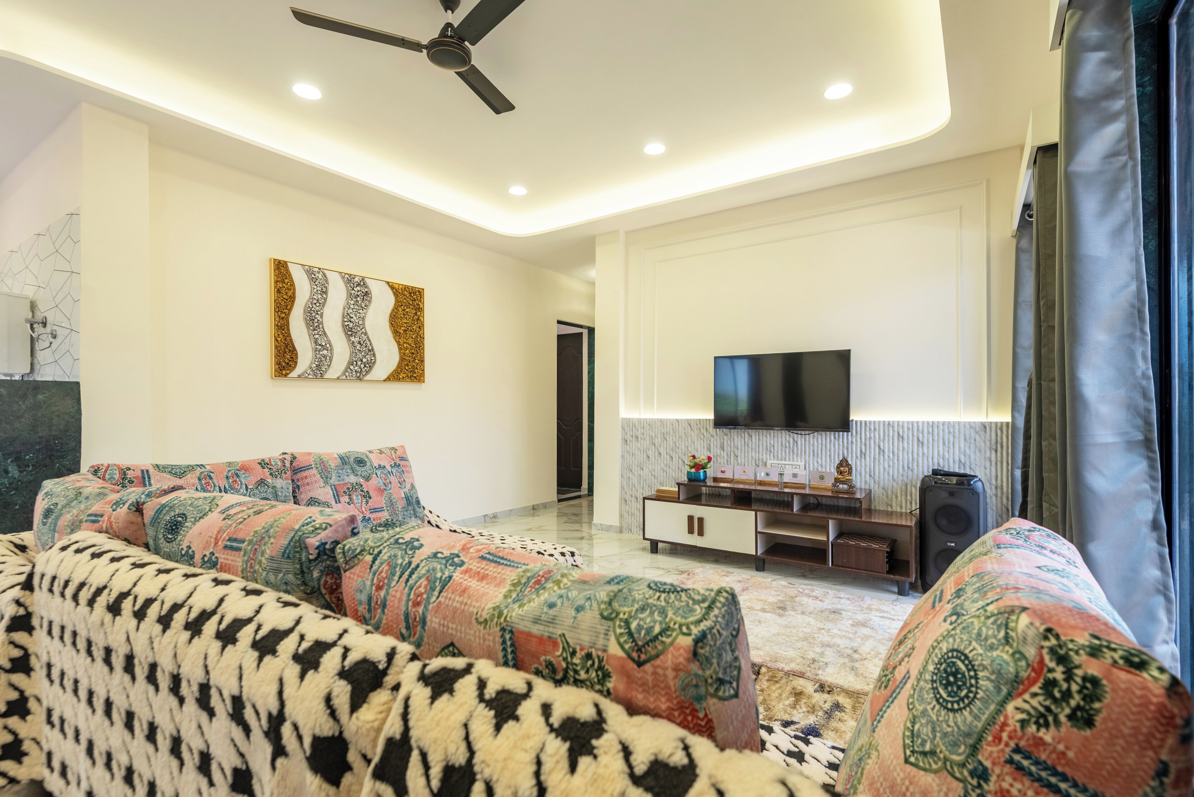 A modern living room with a sofa, TV, and ceiling fan.