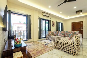 A living room with a sofa, a coffee table with a book, a decorative bowl, and a patterned rug. - Ansh Villa Luxury 4-BHK Pet-friendly (Jambrung)