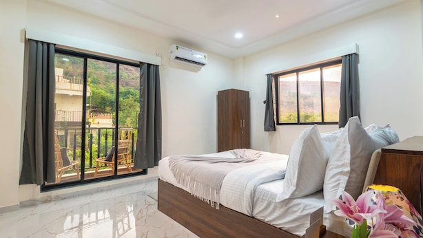 Un dormitorio con cama, armario, ventana con vistas y balcón con sillas.