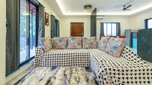 Una sala de estar moderna con un juego de sofá, ventanas amplias y un ventilador de techo.