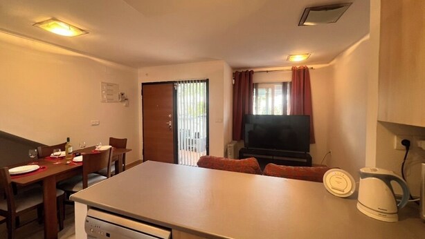 Un espacio habitable compacto con kitchenette, comedor y televisor.