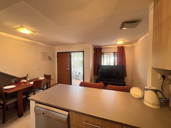 A compact living space with a kitchenette, dining area, and a television.