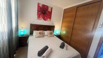 Une chambre d’hôtel avec un lit, deux lampes de chevet, une armoire en bois et une grande œuvre d’art à motifs floraux accrochée au mur.