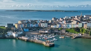 A coastal town with a harbor, buildings, and a prominent church spire.