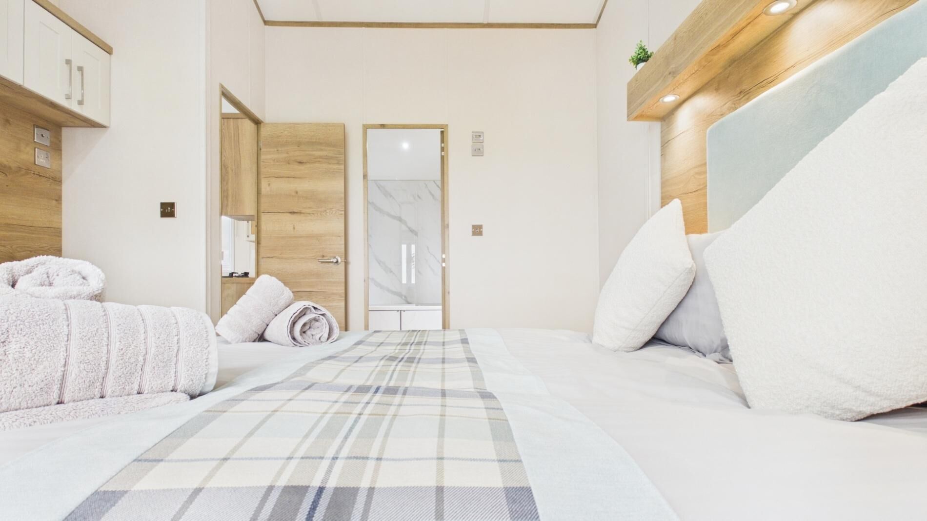 Una habitación de hotel con una cama, dos almohadas, un edredón y un cabecero de madera.