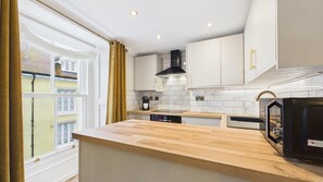 Una cocina moderna con armarios blancos, encimera de madera y campana extractora negra.