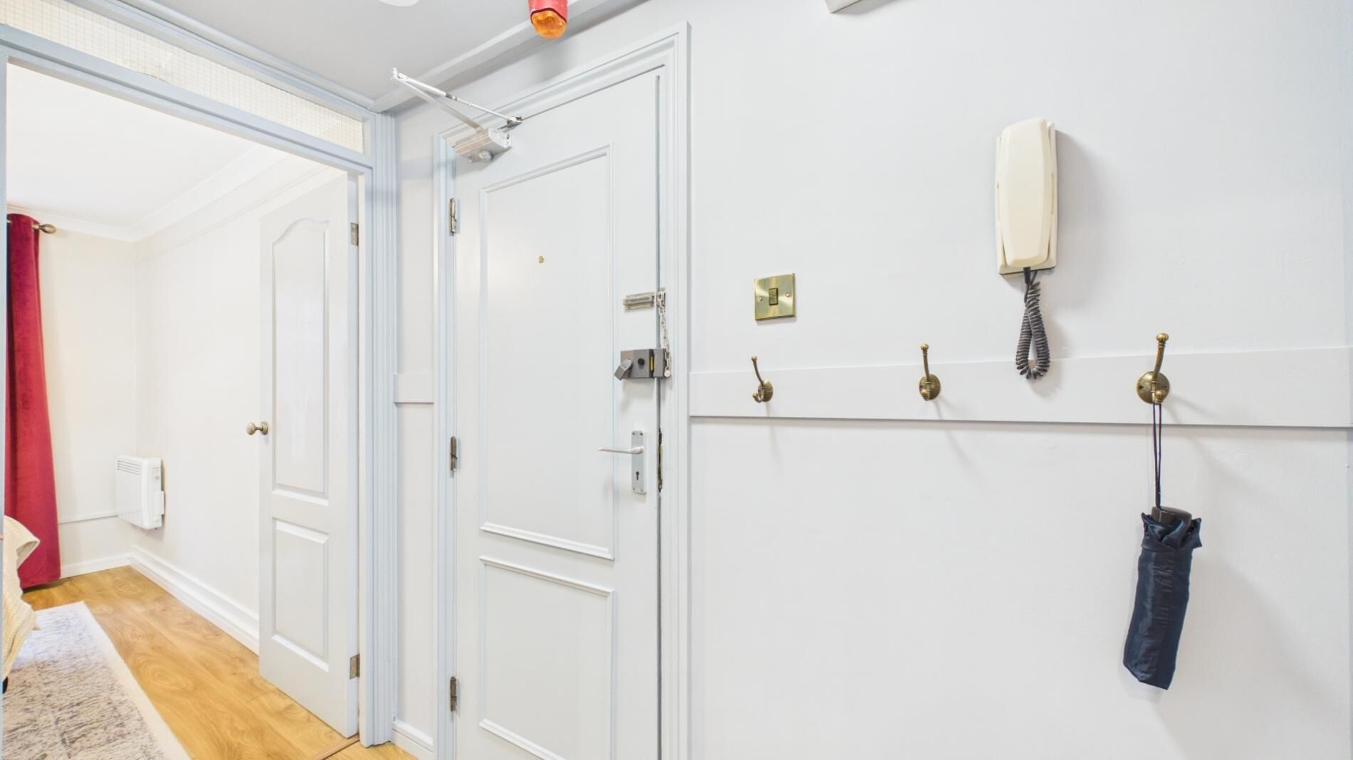A hallway with white doors, a coat hook, a telephone, and a radiator.