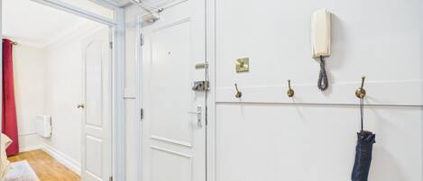 A hallway with white doors, a coat hook, a telephone, and a radiator.
