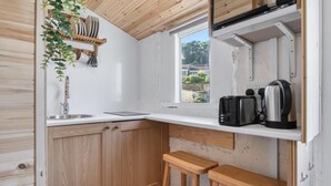Eine kleine Küche mit Holzschränken, einem Fenster und einer Arbeitsplatte mit Wasserkocher und Toaster.