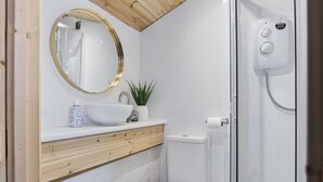 Ein Badezimmer mit weißem Waschbecken, einem Spiegel mit goldener Rahmung, einer Toilette und einer Duschkabine.