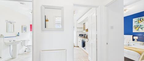 Una habitación de hotel moderna con baño, kitchenette y un dormitorio con cama y mesita de noche.