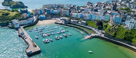 An aerial view of a coastal town with a marina, historic buildings, and a prominent church spire.