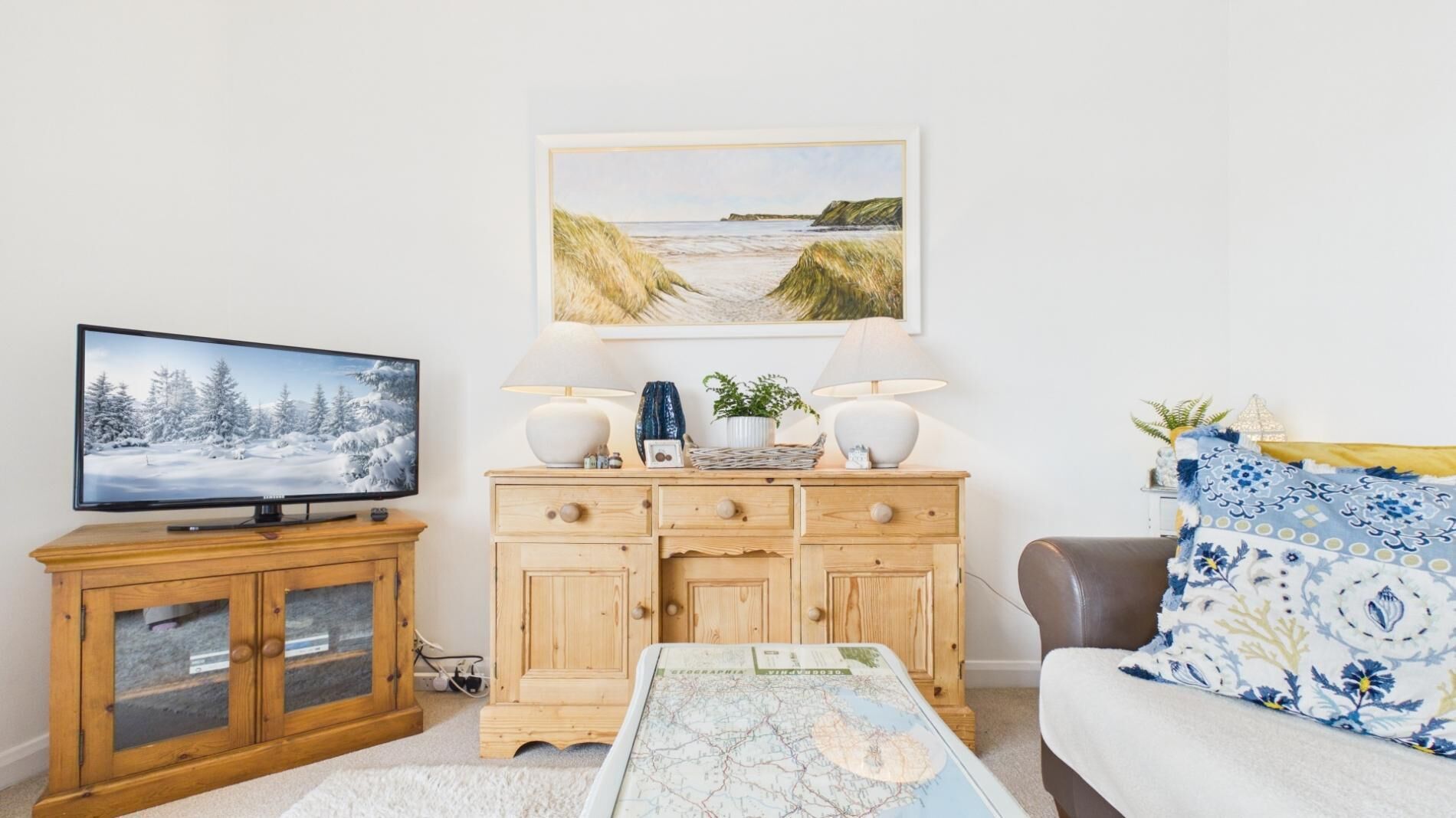 A living room with a television, wooden cabinet, and a sofa.