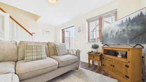 Un salon avec un canapé, un téléviseur, un meuble en bois et un escalier.