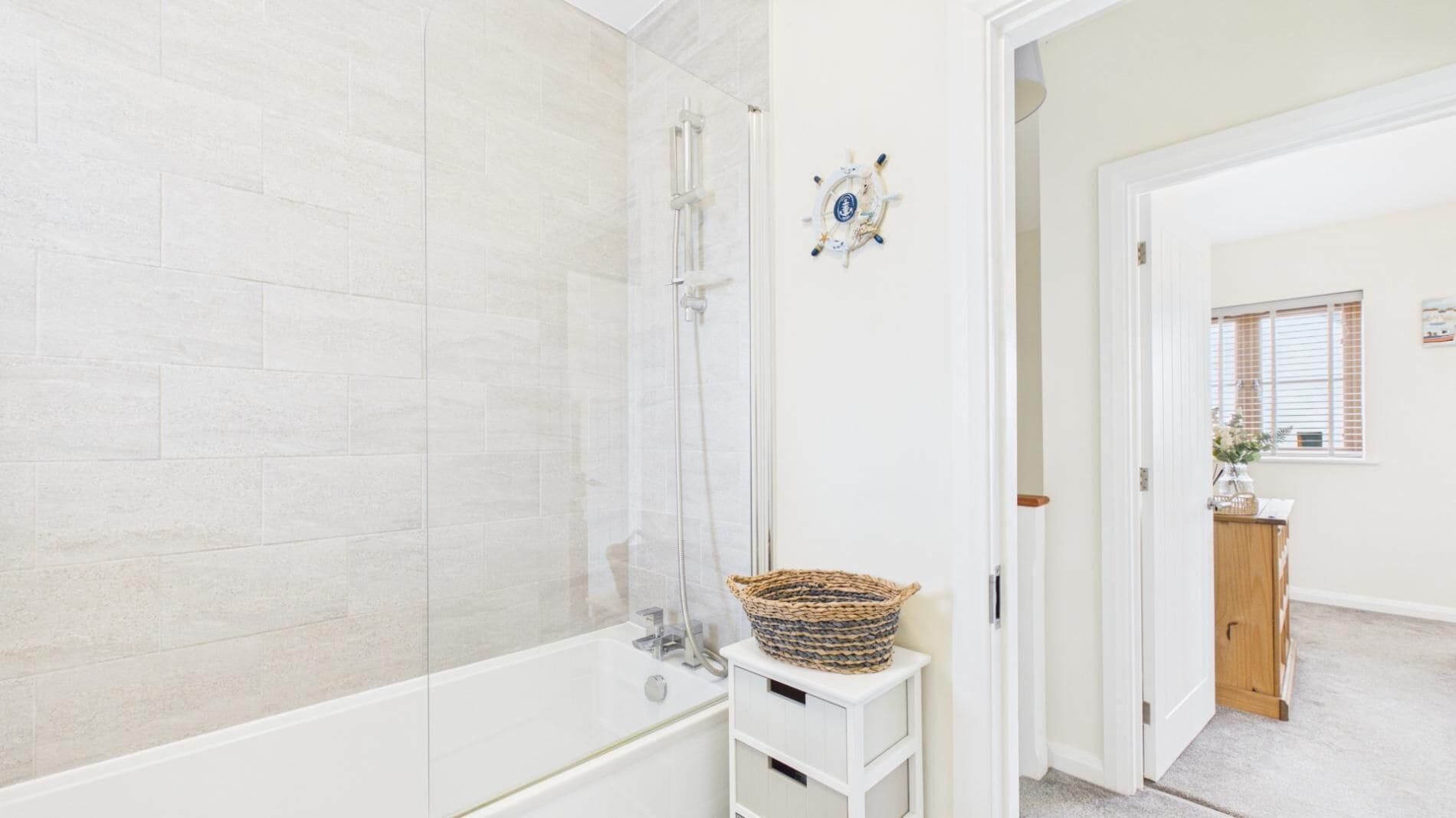 Un baño con bañera, ducha y pared cubierta de azulejos blancos.