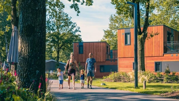 Una familia caminando por un sendero pavimentado en una zona residencial con casas modernas de madera.