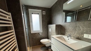 Un baño moderno con inodoro, lavamanos y zona de ducha.