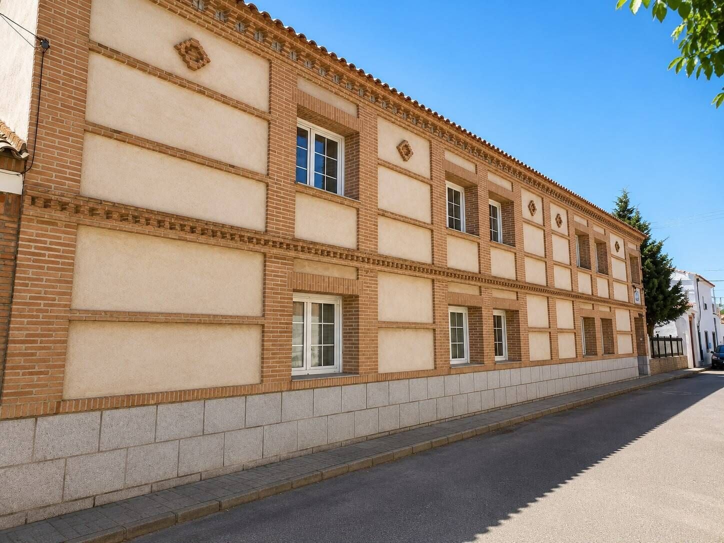 Un edificio de dos plantas con fachada simétrica, que presenta una serie de ventanas y detalles decorativos.