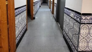 A hallway with patterned tiles, wooden doors, and a tiled floor.