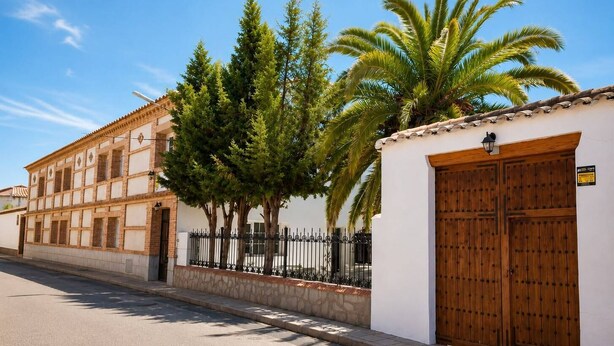 A building with a white facade, a wooden door, and a stone wall.