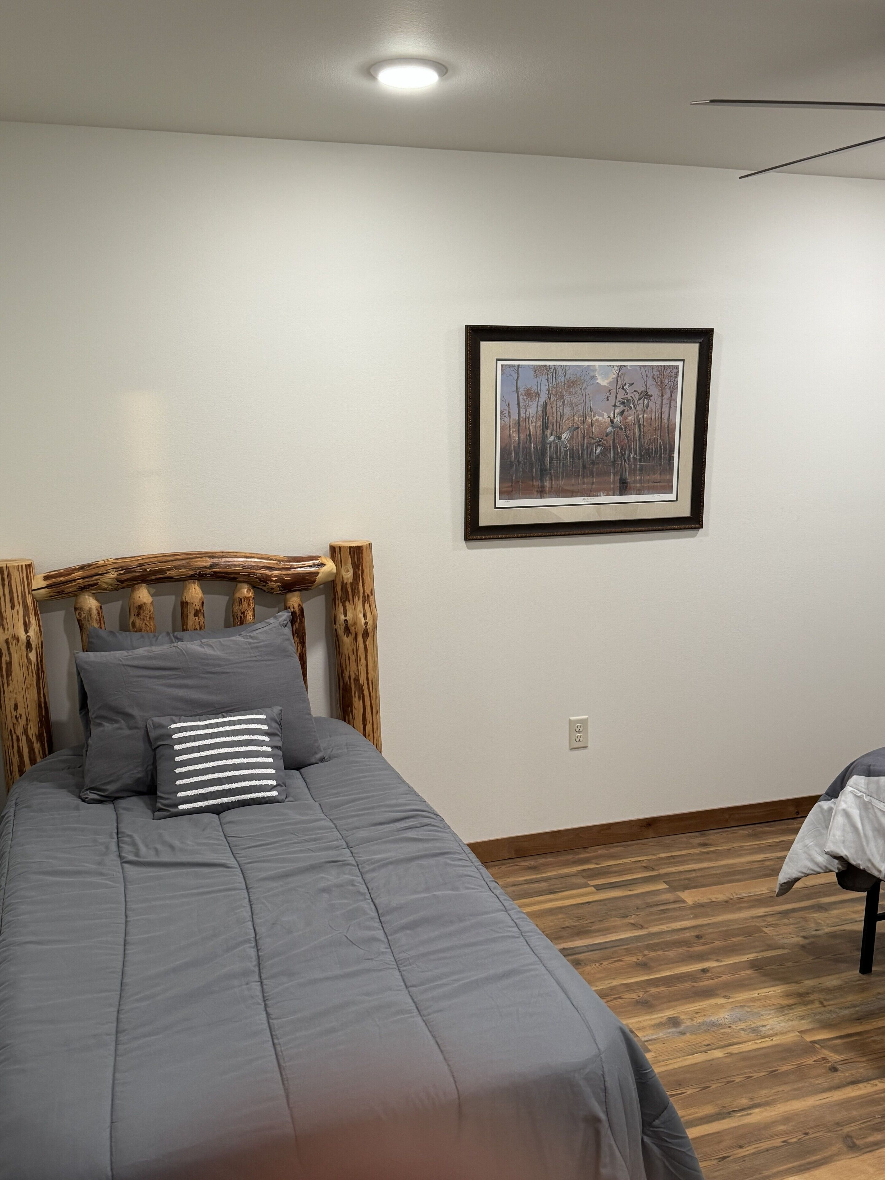 A bedroom with a bed, a framed picture on the wall, and a wooden headboard.