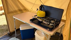 A portable camping stove with a kettle on a table inside a tent. - Daisys Meadow Retreat Sleeps 2 With Hot Tub (Ashford)