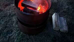A campfire in a metal pot with logs nearby. - Daisys Meadow Retreat Sleeps 2 With Hot Tub (Ashford)
