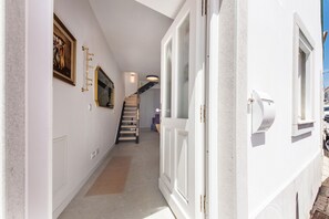 Ein Flur mit Treppe, einer Tür und einem an der Wand hängenden Bilderrahmen.