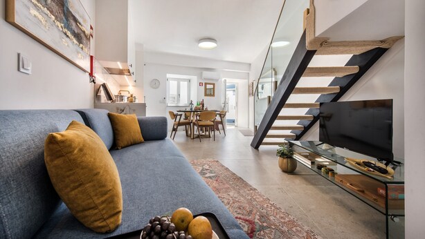 A modern living room with a sofa, a coffee table with fruits, a TV, and a staircase. - Casa Portuguesa in Tavira (Tavira)
