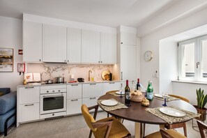 Eine moderne Küche mit weißen Schränken, einem für vier Personen gedeckten Esstisch und einer Uhr an der Wand.