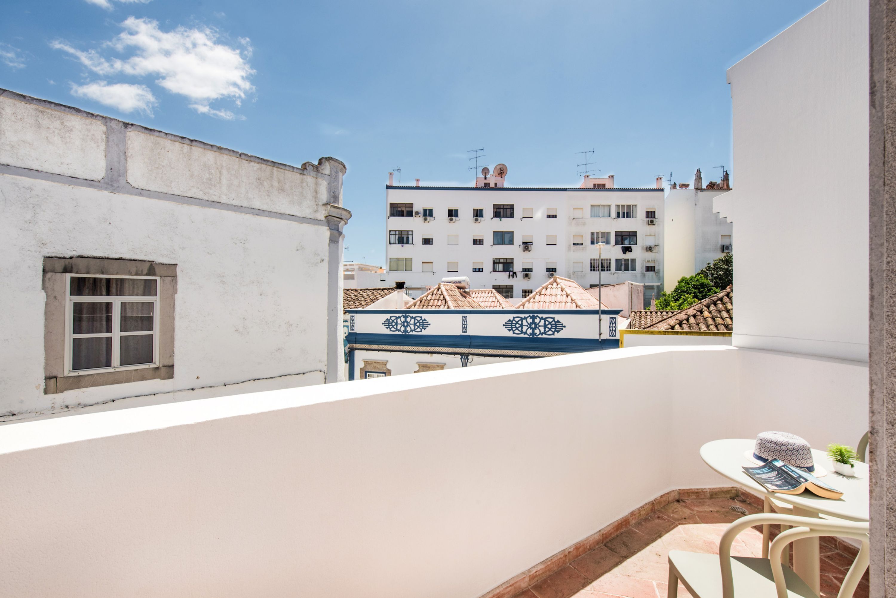 A balcony with a table, chairs, and a small plant.