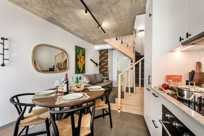 Eine moderne Küche mit weißen Schränken, einem Holztisch und einer Treppe, die in eine andere Ebene führt.