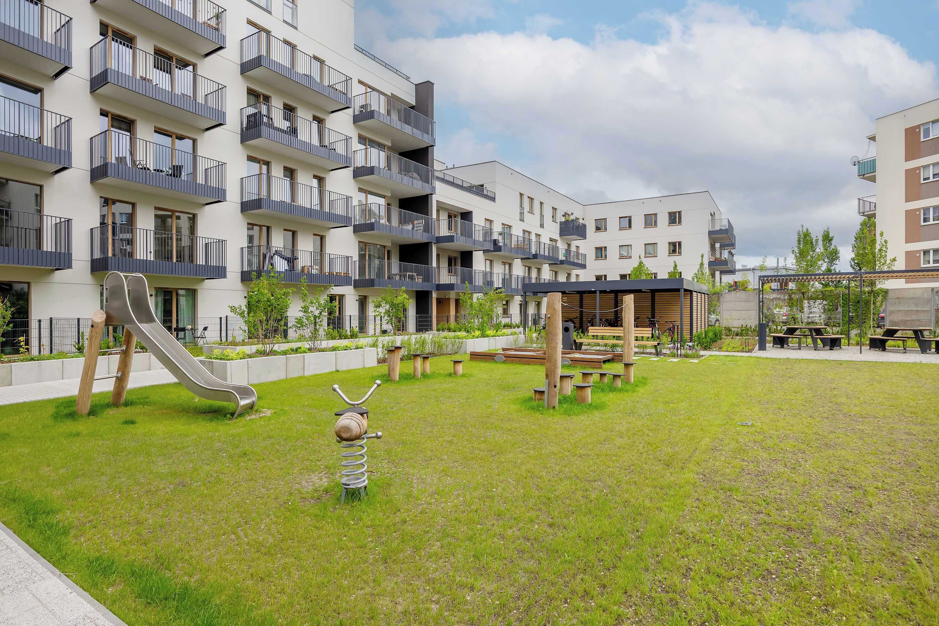 Un immeuble d’appartements moderne doté de balcons, d’une aire de jeux et d’espaces de détente en plein air.