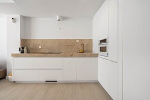 A modern kitchen with white cabinetry, a marble backsplash, and a built-in oven. - RDR513 - Beautiful 1 Bedroom Apt. in Atica Homes Estepona (Estepona)