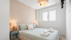 Une chambre à coucher comprenant un lit, deux lampes de chevet, une fenêtre et un projecteur fixé au mur.