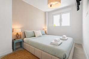 A bedroom with a bed, two bedside lamps, a window, and a wall-mounted projector. - RDR513 - Beautiful 1 Bedroom Apt. in Atica Homes Estepona (Estepona)