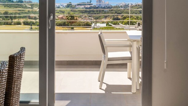 A room with a sliding glass door leading to a balcony with a view of the sea and distant landscape. - RDR559 - Seaview 2 Bed Apartment in Habitat Valle Romano (Estepona)