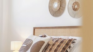 A neatly made bed with a wooden headboard, a bedside lamp, and a wall with circular wall art. - RDR559 - Seaview 2 Bed Apartment in Habitat Valle Romano (Estepona)