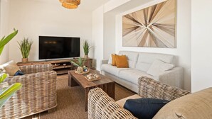 A living room with a sofa, coffee table, TV, and decorative wall art. - RDR559 - Seaview 2 Bed Apartment in Habitat Valle Romano (Estepona)