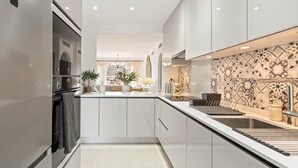 A modern kitchen with white cabinetry, a central island, and a patterned backsplash. - RDR548 - Stylish 2 bed apt in La Ola (Marbella)