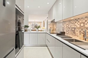 A modern kitchen with white cabinetry, a central island, and a patterned backsplash. - RDR548 - Stylish 2 bed apt in La Ola (Marbella)