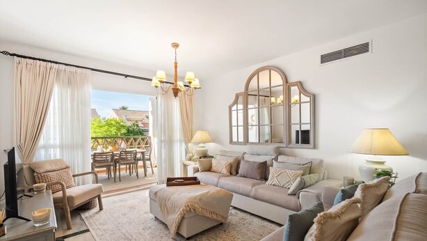 A living room with a sofa, ottoman, and a dining area with chairs and a table. - RDR548 - Stylish 2 bed apt in La Ola (Marbella)