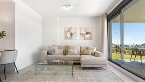 Ein modernes Wohnzimmer mit einer Couch, einem Glastisch und Blick ins Freie.