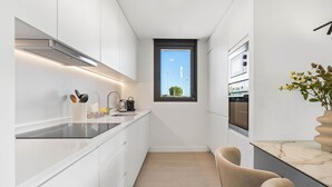 Eine moderne Küche mit weißen Schränken, einer schwarzen Arbeitsplatte, einem Fenster und einer Marmor-Spritzschutzwand.